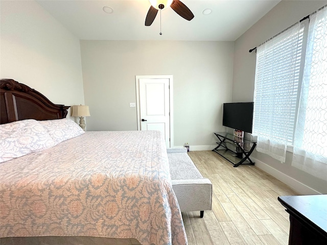 bedroom featuring multiple windows, ceiling fan, light wood-style flooring, and baseboards