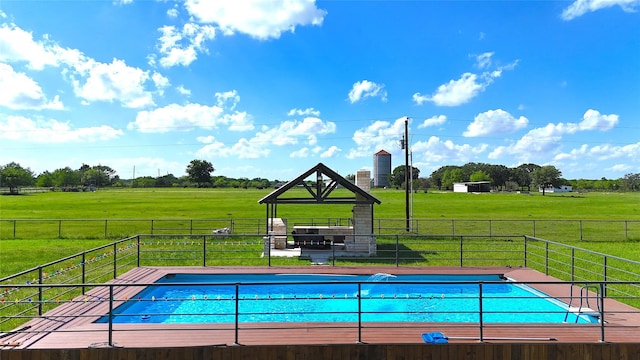 view of swimming pool with a rural view, fence, and a yard