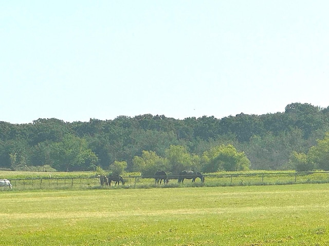 surrounding community featuring a rural view, fence, and a lawn