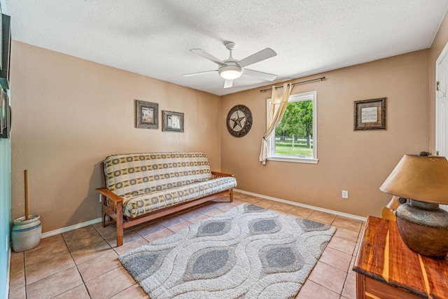 sitting room with tile flooring, ceiling fan, and a textured ceiling