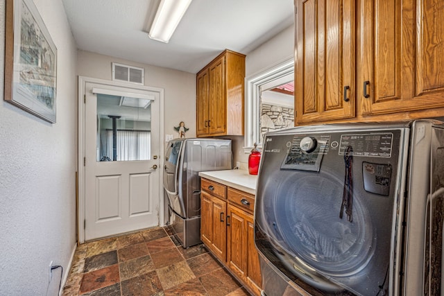 laundry room featuring cabinets, independent washer and dryer, and dark tile flooring