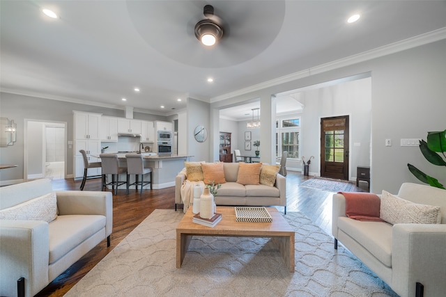 living room with hardwood / wood-style floors, ceiling fan with notable chandelier, and ornamental molding