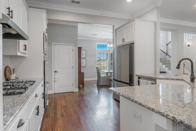 kitchen featuring dark hardwood / wood-style flooring, white cabinetry, light stone counters, and appliances with stainless steel finishes