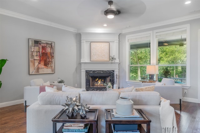 living room featuring a high end fireplace, dark hardwood / wood-style flooring, ceiling fan, and crown molding