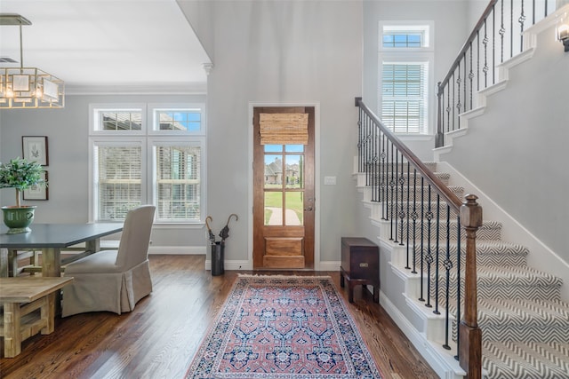 foyer entrance featuring crown molding, dark wood-type flooring, and a chandelier