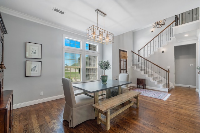 dining area with dark wood-type flooring, a notable chandelier, and ornamental molding