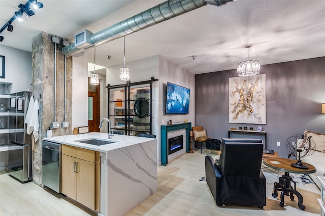 kitchen featuring dishwasher, light stone countertops, sink, and hanging light fixtures