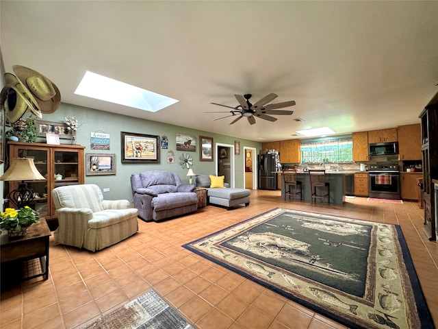 tiled living room featuring ceiling fan and a skylight