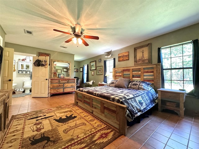 bedroom with tile patterned flooring, visible vents, ceiling fan, and a textured ceiling