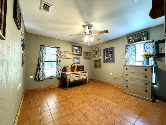 interior space with a textured ceiling, light tile patterned floors, visible vents, and baseboards