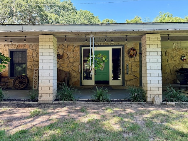 view of exterior entry with covered porch and stone siding