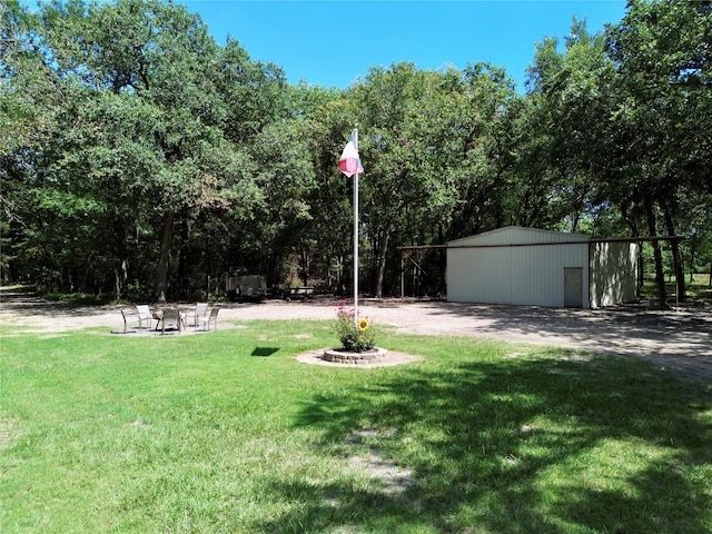 view of yard with an outdoor structure and an outdoor fire pit