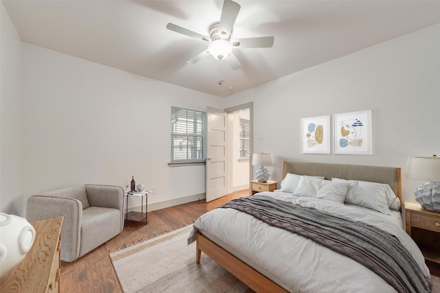 bedroom with ceiling fan, wood finished floors, and baseboards