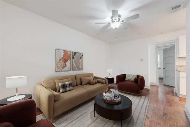 living room with light wood-style floors, visible vents, ceiling fan, and baseboards