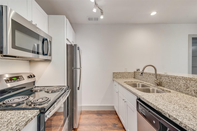 kitchen featuring visible vents, appliances with stainless steel finishes, white cabinets, a sink, and wood finished floors