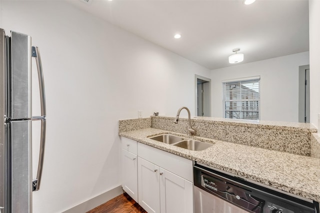 kitchen featuring white cabinetry, appliances with stainless steel finishes, light stone counters, and a sink