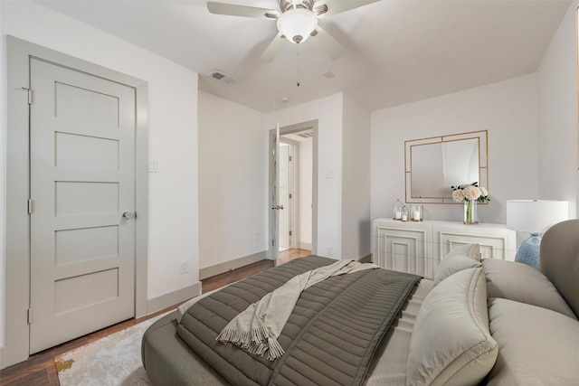 bedroom featuring a ceiling fan, visible vents, baseboards, and wood finished floors