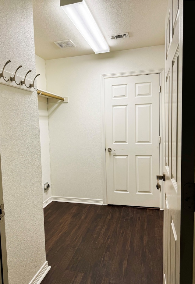 laundry area with dark hardwood / wood-style flooring and a textured ceiling