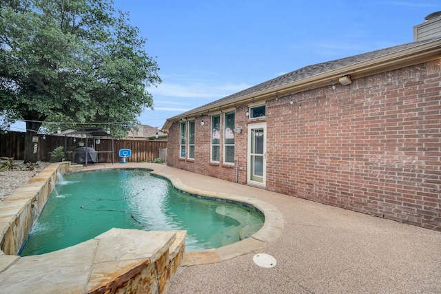 view of swimming pool with pool water feature and a patio