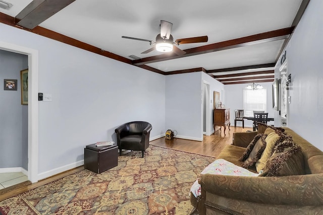 living room with beam ceiling, light hardwood / wood-style flooring, and ceiling fan with notable chandelier