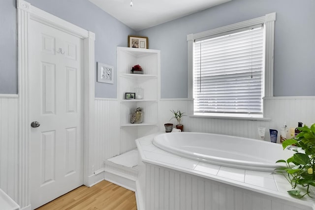 bathroom with a bathing tub, hardwood / wood-style floors, and a healthy amount of sunlight