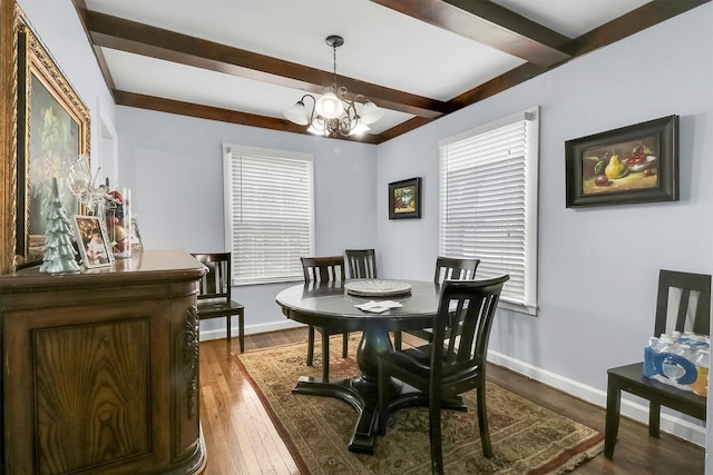 dining space featuring beam ceiling, a wealth of natural light, dark wood-type flooring, and an inviting chandelier