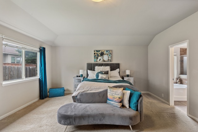 carpeted bedroom featuring ensuite bath and lofted ceiling