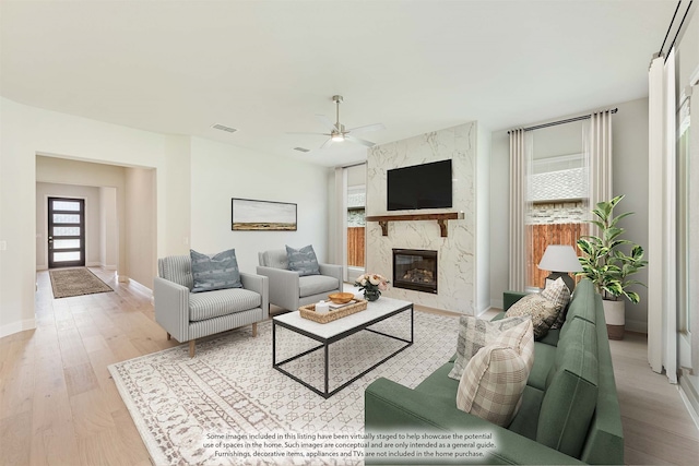 living room featuring ceiling fan, light wood-type flooring, and a fireplace