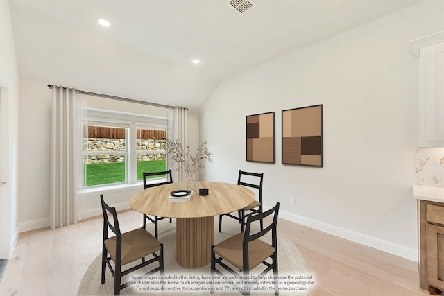 dining area featuring lofted ceiling and light wood-type flooring