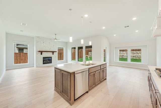 kitchen with a center island with sink, a premium fireplace, stainless steel dishwasher, sink, and ceiling fan