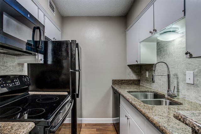 kitchen with light stone counters, sink, black appliances, and white cabinets