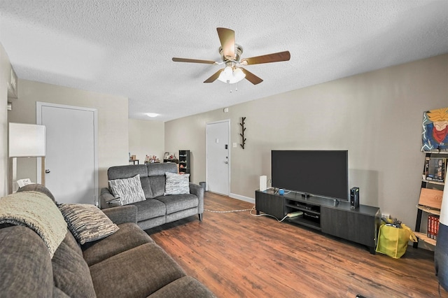 living room featuring dark wood-type flooring, ceiling fan, and a textured ceiling