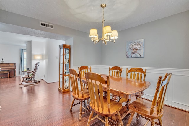 dining area featuring wood-type flooring, a textured ceiling, and an inviting chandelier