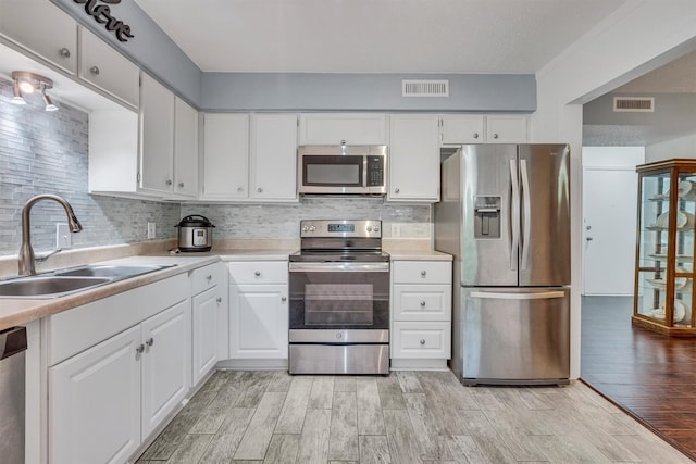 kitchen with stainless steel appliances, white cabinetry, tasteful backsplash, and sink