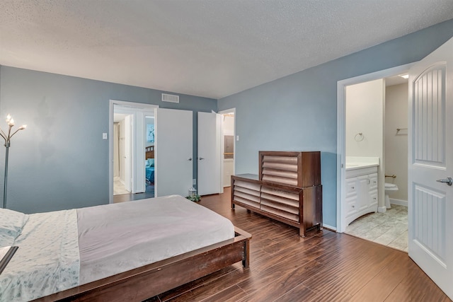 bedroom with hardwood / wood-style floors, a textured ceiling, and ensuite bath