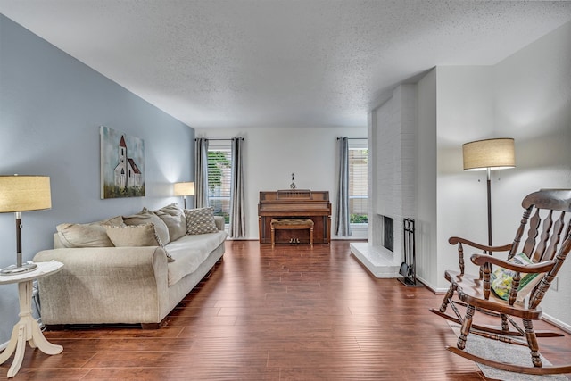 living room with dark hardwood / wood-style flooring, a large fireplace, and a textured ceiling