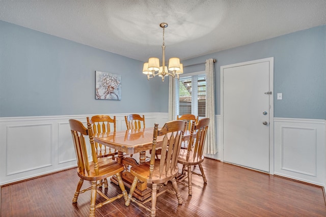 dining area featuring wood-type flooring, a textured ceiling, and an inviting chandelier