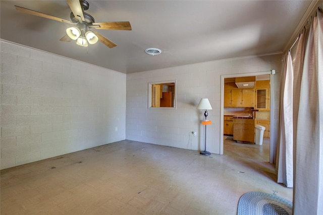 empty room featuring concrete block wall, visible vents, and ceiling fan