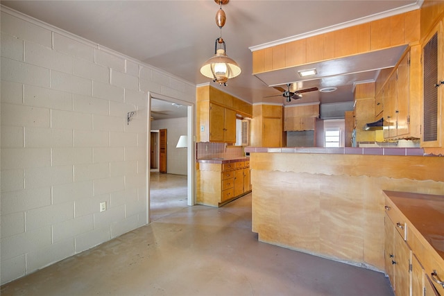 kitchen featuring finished concrete flooring, concrete block wall, brown cabinets, a peninsula, and hanging light fixtures