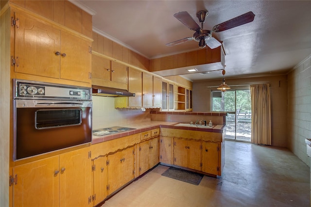 kitchen with crown molding, tile countertops, a peninsula, oven, and under cabinet range hood