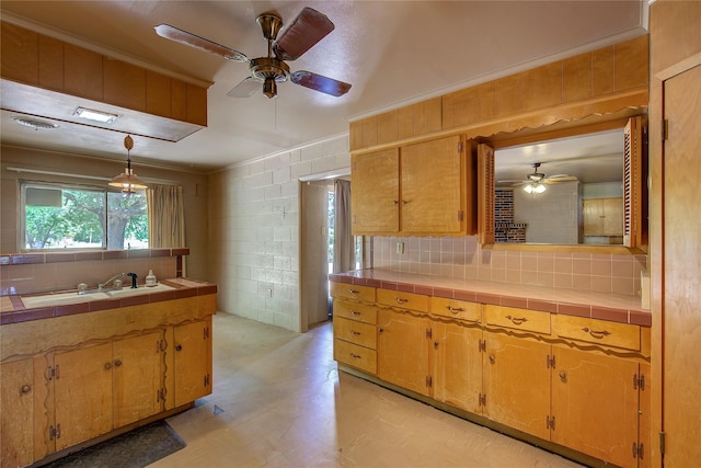 kitchen with tile countertops, light floors, tasteful backsplash, hanging light fixtures, and a sink