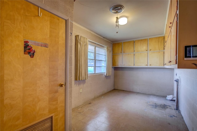 spare room featuring concrete block wall and visible vents