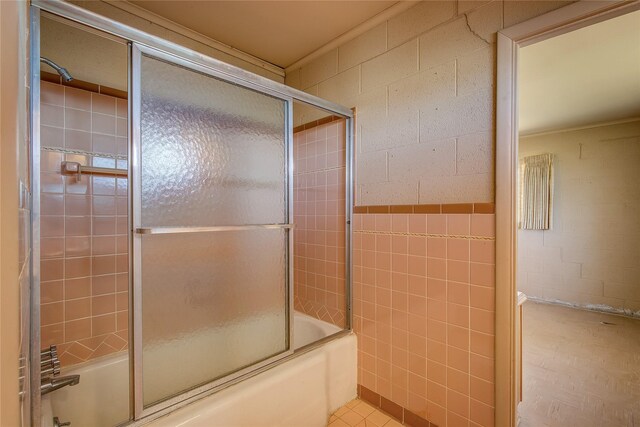 bathroom featuring tile walls, tile patterned floors, and bath / shower combo with glass door