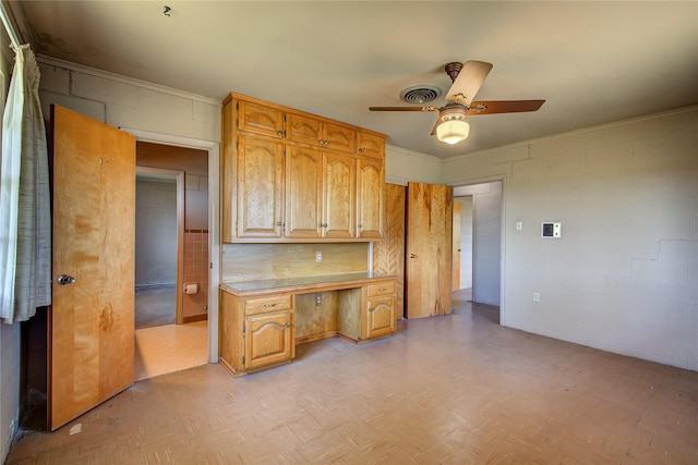 kitchen with concrete block wall, built in desk, light countertops, visible vents, and a ceiling fan