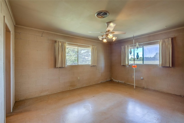 unfurnished room featuring a ceiling fan, plenty of natural light, visible vents, and concrete block wall