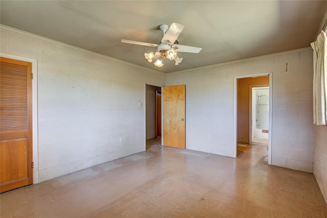 spare room with a ceiling fan and concrete block wall