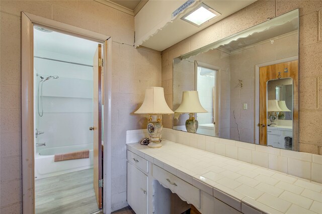 bathroom featuring hardwood / wood-style floors,  shower combination, vanity, and tile walls