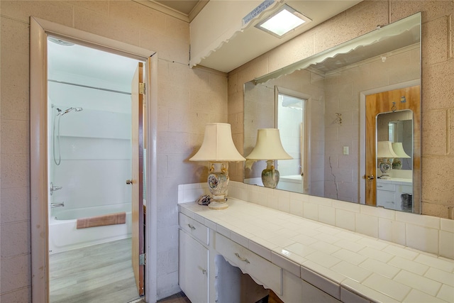 bathroom featuring washtub / shower combination, vanity, and wood finished floors