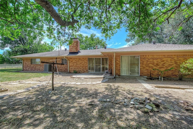 rear view of property featuring a patio, a chimney, fence, central AC, and brick siding