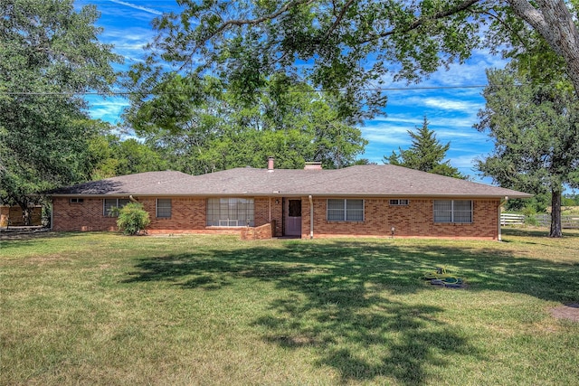 ranch-style home with a shingled roof, a chimney, a front lawn, and brick siding